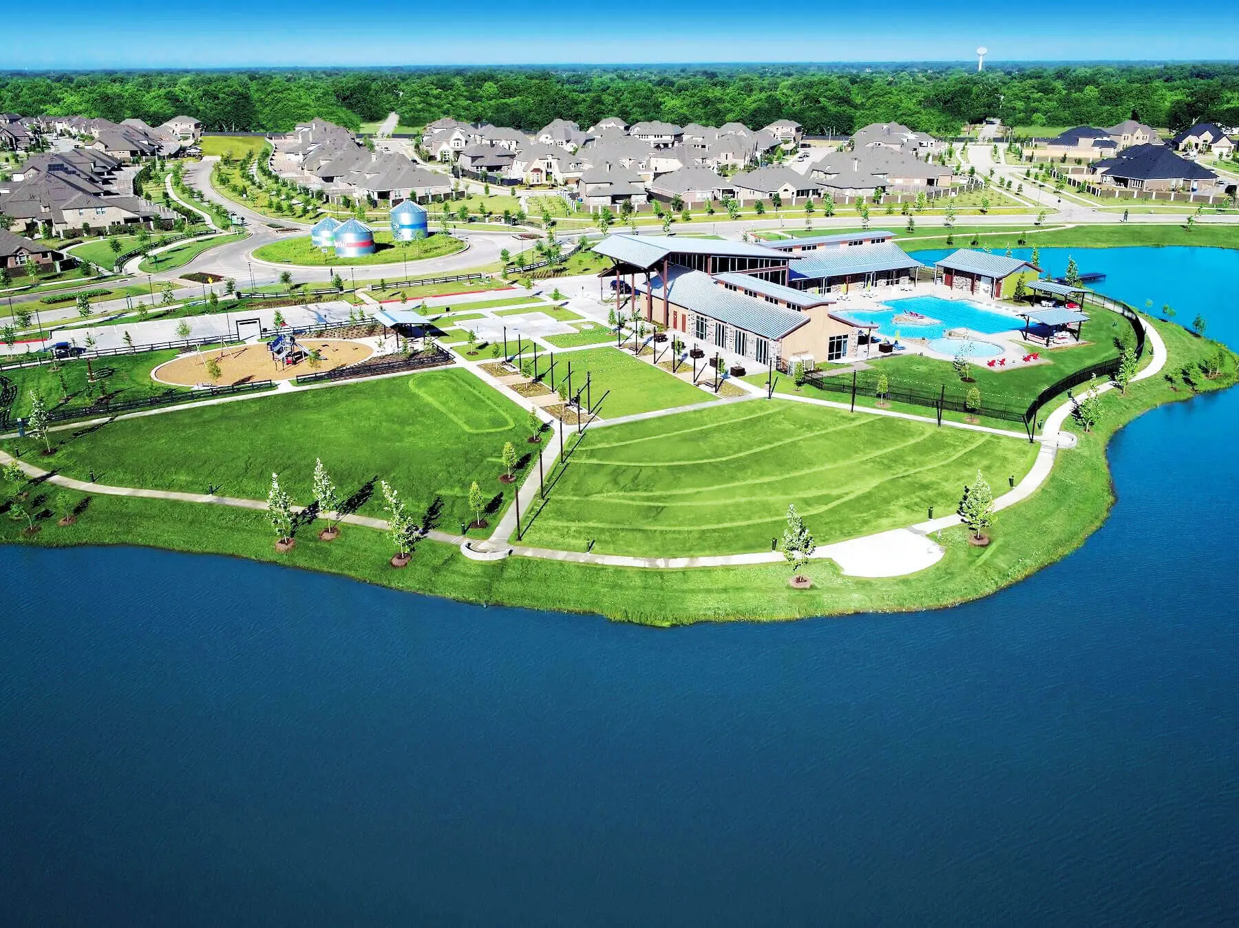 Aerial view of a Texas municipal utility district amenity center with a community pool, park grounds, and lake